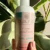 Close up of Curl Flo Moisturising Curl Cream against a leafy background for soft, supple curls